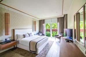 Une chambre d’hôtel avec un grand lit, une télévision, un bureau et une vue sur la verdure.