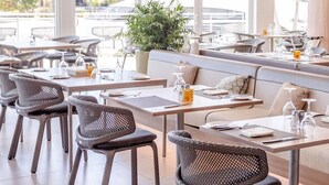 A restaurant with wicker chairs, tables, and a large potted plant. - Hilton At Resorts World Bimini (Alice Town)