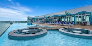 Un espace piscine avec des chaises longues et un bâtiment doté de grandes fenêtres.