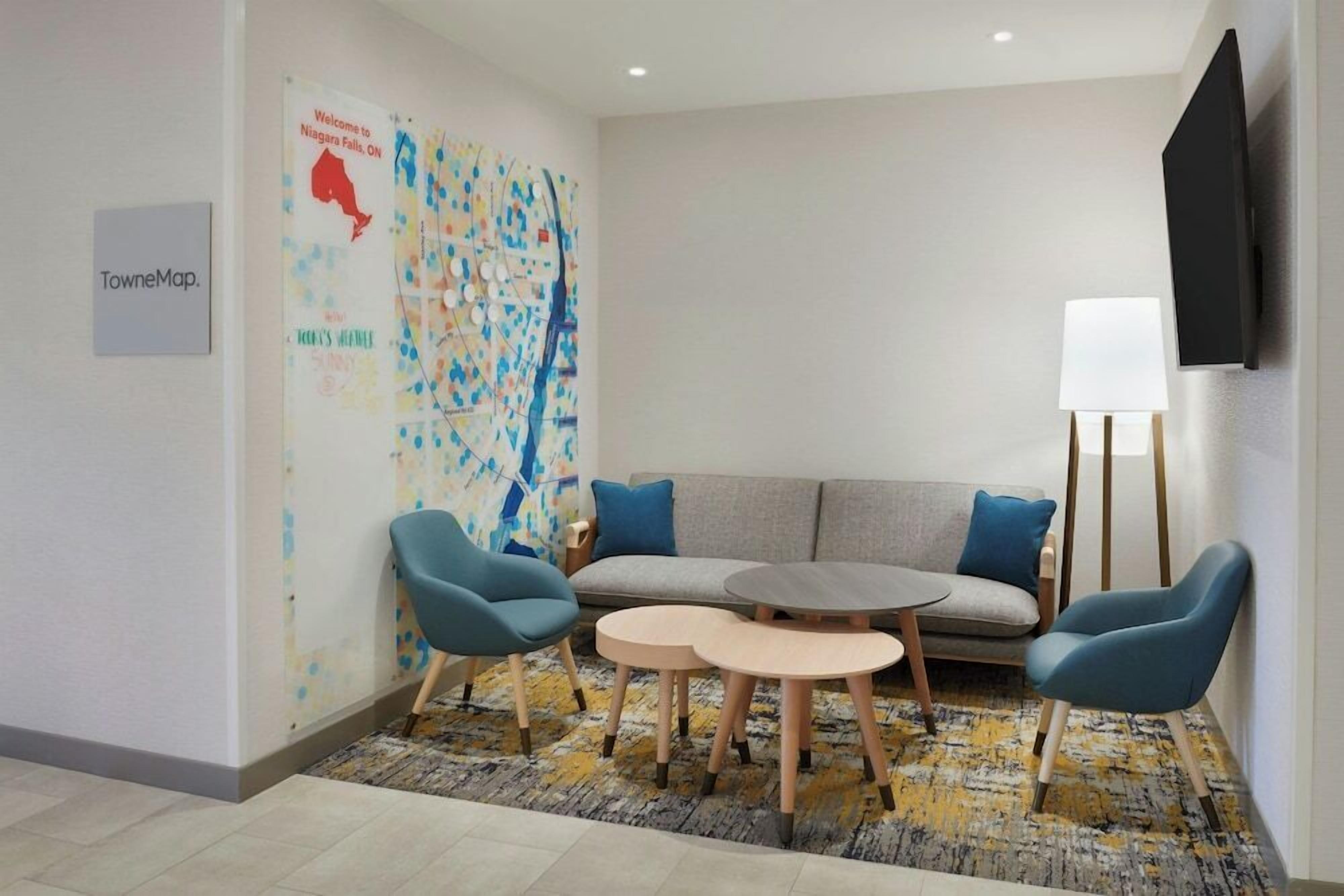Habitación de hotel con sofá, dos sillones, una mesita y un mapa en la pared, además de un televisor de pantalla plana.