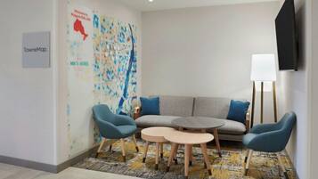 Habitación de hotel con sofá, dos sillones, una mesita y un mapa en la pared, además de un televisor de pantalla plana.