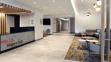 Zona de recepción de hotel con mostrador, área de estar y pasillo que conduce a otras habitaciones.
