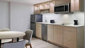 A modern kitchen with a microwave, refrigerator, dishwasher, and a dining area with a table and chairs.
