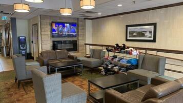 A hotel lobby with seating, a TV, a fireplace, and a shoe rack.