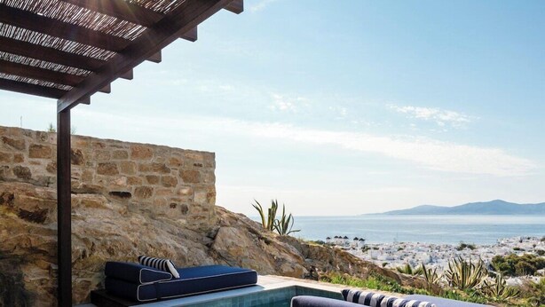 A stone wall, a pool, and a view of the sea. - Anandes Hotel - Adults Only (Mykonos)