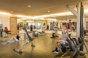 Une salle de sport équipée de matériel d’exercice, de miroirs et dotée d’un plancher en bois.