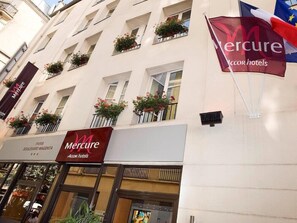 A hotel with balconies, a sign for Mercure Accor hotels, and a flag. - Mercure Boulevard Magenta (Paris)