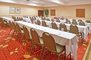 A conference room with rows of tables and chairs, a patterned carpet, and framed pictures on the wall. - Wyndham Flint Mi/grand Blanc/bishop Airport/conference Ctr (Flint)