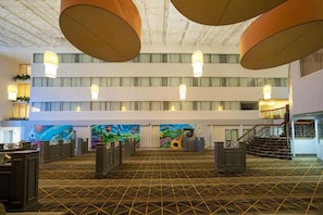 A hotel lobby with a high ceiling, multiple levels, and a patterned floor. - Wyndham Flint Mi/grand Blanc/bishop Airport/conference Ctr (Flint)