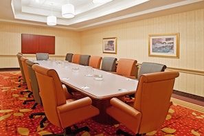 A conference room with a long table, multiple chairs, and a wooden cabinet. - Wyndham Flint Mi/grand Blanc/bishop Airport/conference Ctr (Flint)