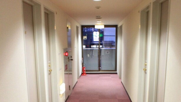 A hallway with carpeted floors and doors on both sides. - Ascent Inn Sapporo (Sapporo)
