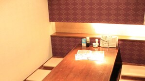 A conference room with a long wooden table, cushioned chairs, and a patterned wall. - Ascent Inn Sapporo (Sapporo)
