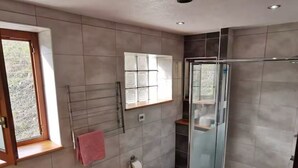 Moderni kylpyhuone, jossa on lasinen suihkuseinä, wc, pesuallas ja pyyhekoukku.