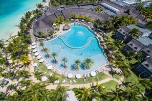 An aerial view of a resort with a large circular pool surrounded by palm trees and lounge chairs. - LUX Belle Mare Resort and Villas (Belle Mare)