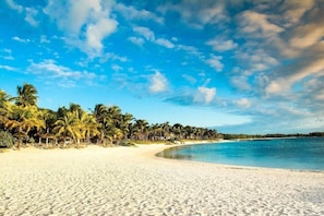 A beach with white sand, palm trees, and a clear blue sky. - LUX Belle Mare Resort and Villas (Belle Mare)