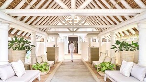 A corridor with white sofas and planters, leading to a room with a thatched roof. - LUX Belle Mare Resort and Villas (Belle Mare)