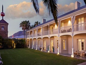 A hotel with a covered outdoor area, multiple balconies, and a tower structure in the background. - Dock House Boutique Hotel (Cape Town)