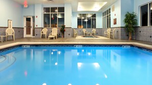 Una piscina con sillas alrededor, una puerta y una planta.