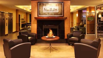 A lobby with a fireplace, leather chairs, a round table, and a reception desk.