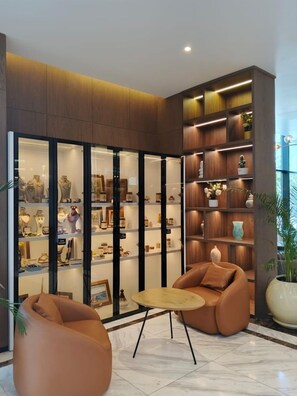 Un interior moderno con una zona de estar, una vitrina con diversos objetos y una planta grande en maceta.