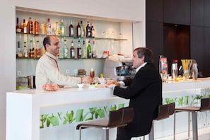 A bar area with a counter, bar stools, and a variety of bottles. - Atlantis Alger Airport (Algiers)