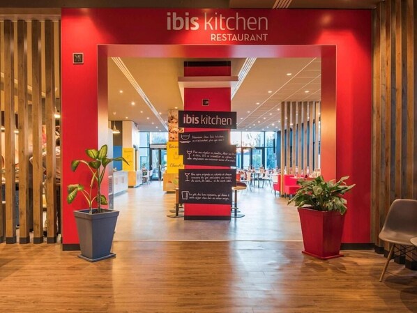 A modern restaurant interior with a red and beige color scheme, wooden accents, and potted plants. - Atlantis Alger Airport (Algiers)