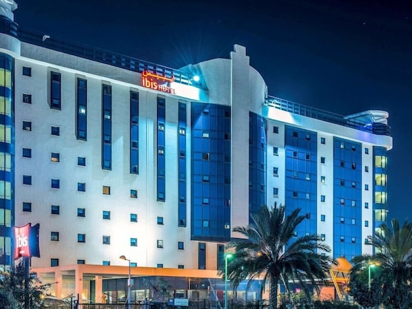 A multi-story hotel with a prominent 'ibis HOTEL' sign, large windows, and a modern architectural design. - Atlantis Alger Airport (Algiers)