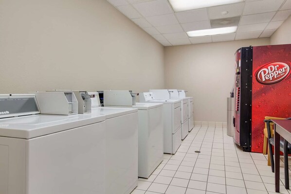 A laundry facility with multiple washing machines and a large red machine labeled 'Dr Pepper.'