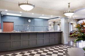 A hotel reception area with a check-in counter, a clock, and a check-in desk.