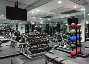 A gym with exercise equipment, mirrors, and a television.