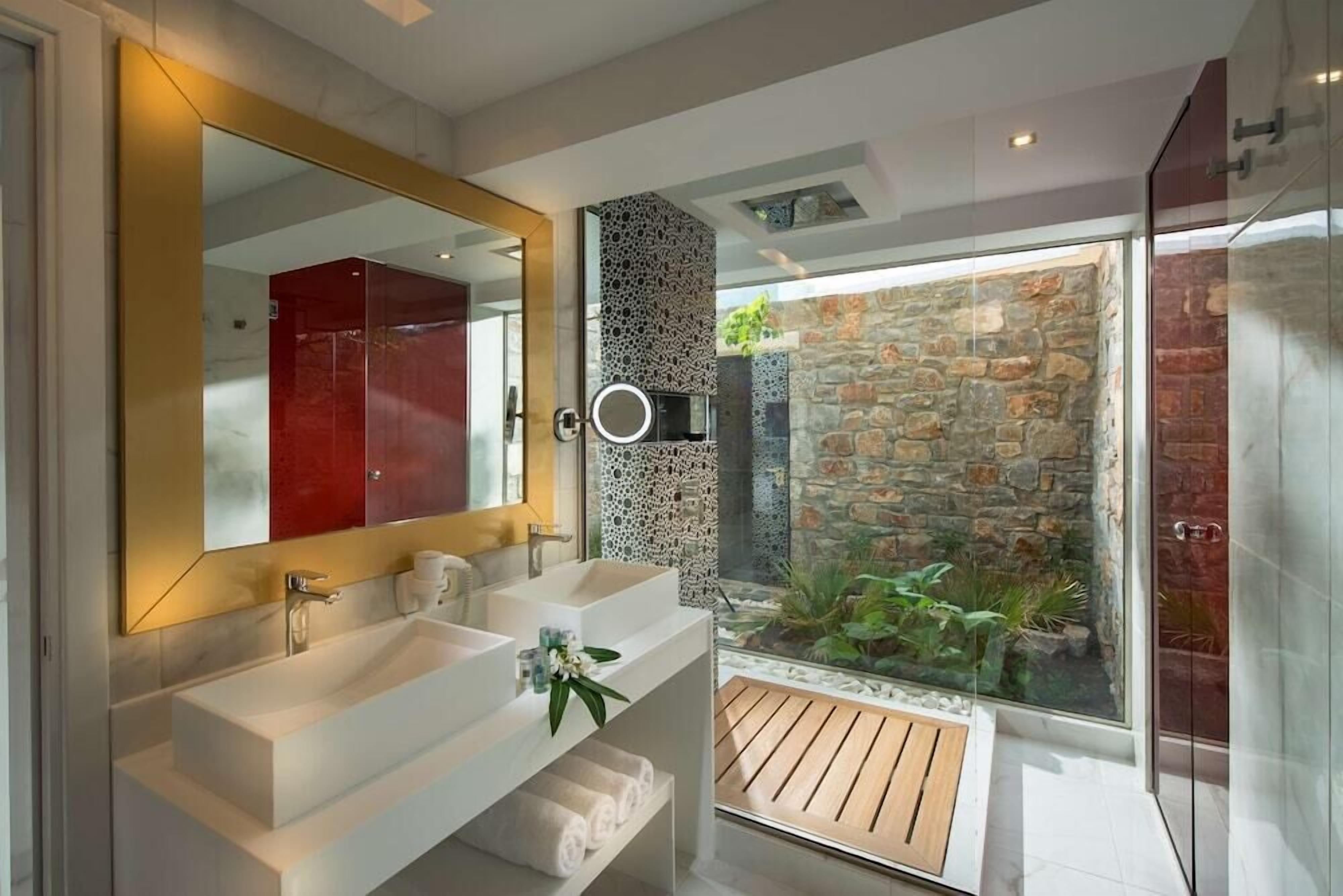 Un baño moderno con dos lavamanos, un espejo grande y una pared de piedra.