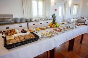 A buffet table with various food items and a fruit display. - Pousada Conde de Ourem (Ourem)