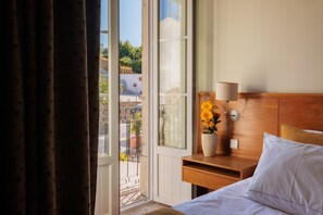 A hotel room with a bed, a nightstand, a lamp, and a window with a view of the outside. - Pousada Conde de Ourem (Ourem)