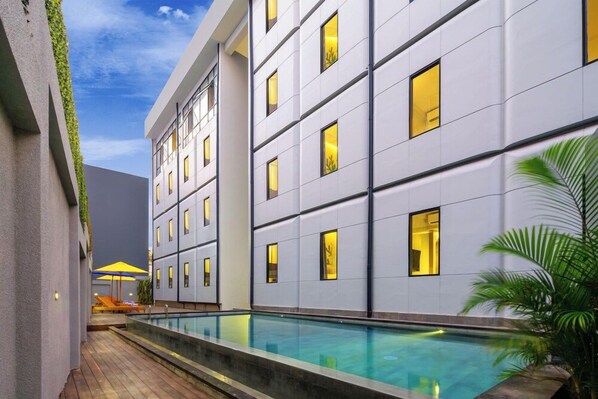 A modern hotel with a swimming pool, multiple balconies, and a view of the sky. - Urban Styles Hitz Kuta (Kuta)