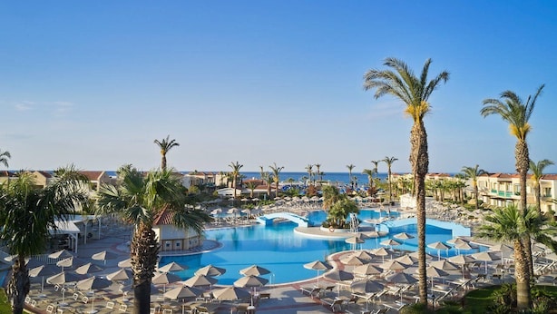A resort with multiple swimming pools, palm trees, and beach views.
