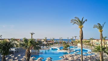 A resort with multiple swimming pools, palm trees, and beach views.