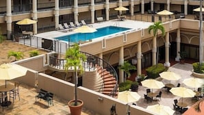 Un hotel con piscina central, zona de estar al aire libre y vistas a un paisaje montañoso verde.