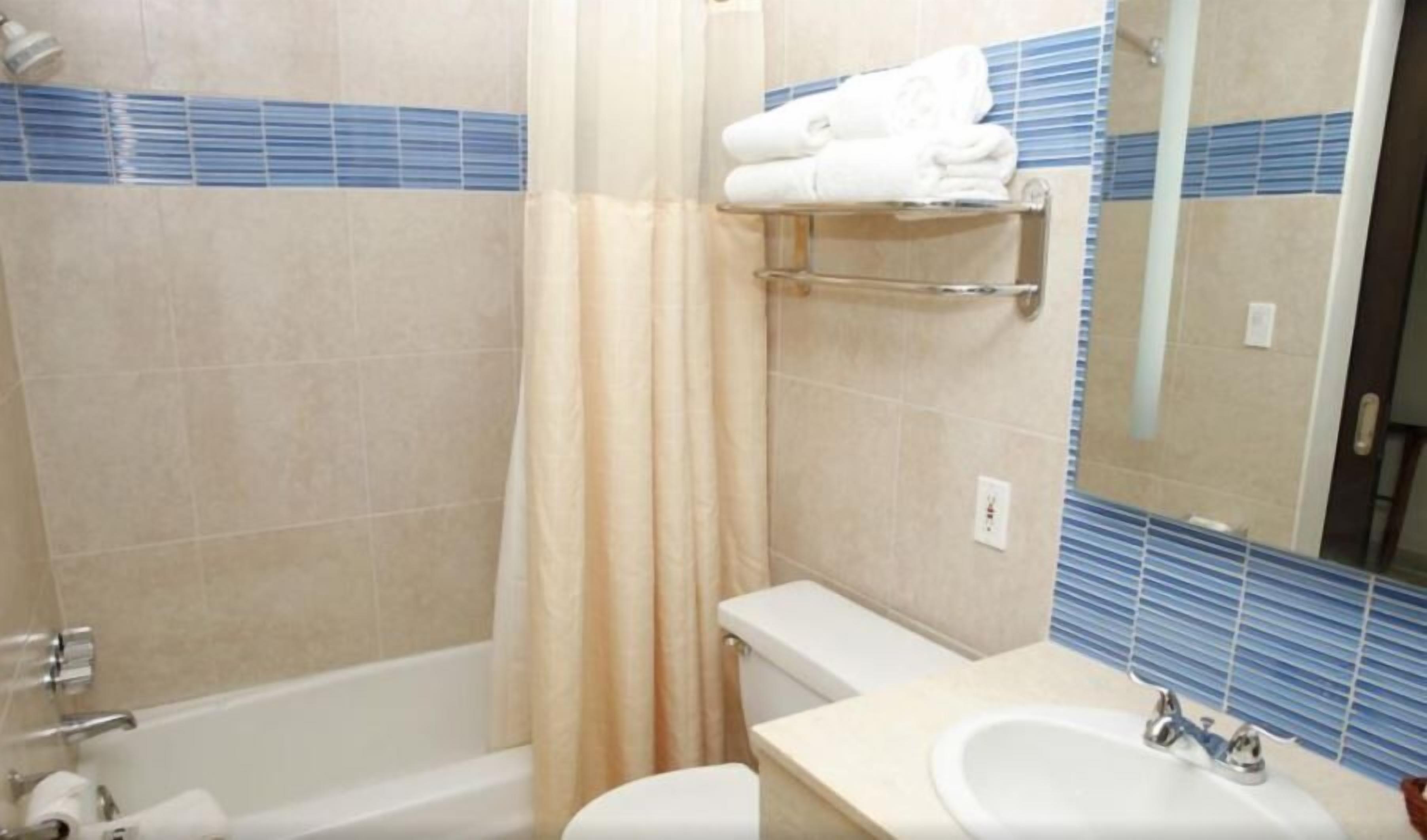 A bathroom with a bathtub, toilet, sink, and a towel rack.