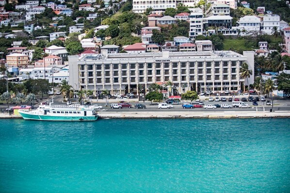 A large hotel with multiple floors, a waterfront view, and a boat docked in front. - Windward Passage Hotel Usvi (St. Thomas)