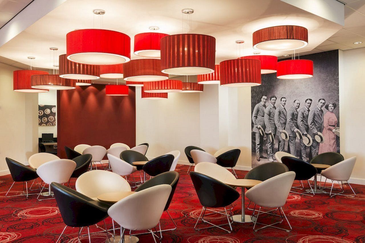 A conference room with modern chairs, red cylindrical pendant lights, and a black and white photograph on the wall.
