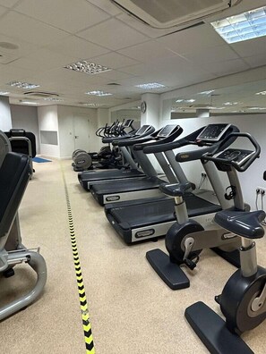 Un gimnasio con cintas de correr, bicicletas estáticas y máquinas de pesas.