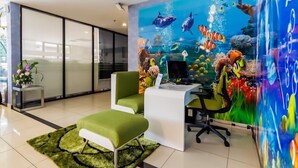 Una oficina moderna con una silla verde, un escritorio y un mural submarino lleno de color.