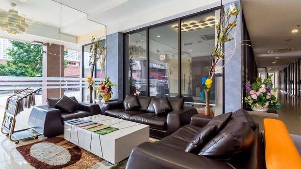 Un vestíbulo moderno con sofás de cuero, una mesa de centro blanca y grandes ventanales con vistas al exterior.