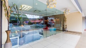 Un moderno vestíbulo de hotel con paredes de vidrio, un jarrón grande y un suelo de baldosas.