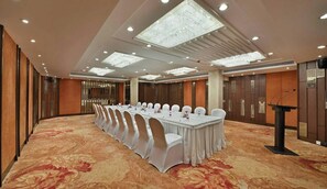 A conference room with a long table, white chairs, and a podium. - Hotel Heritage (Mumbai)