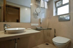 A bathroom with a white sink, mirror, towel rack, and toilet. - Hotel Heritage (Mumbai)