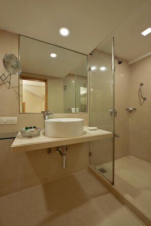 Un baño moderno con cabina de ducha de vidrio, un lavabo blanco y un espejo.