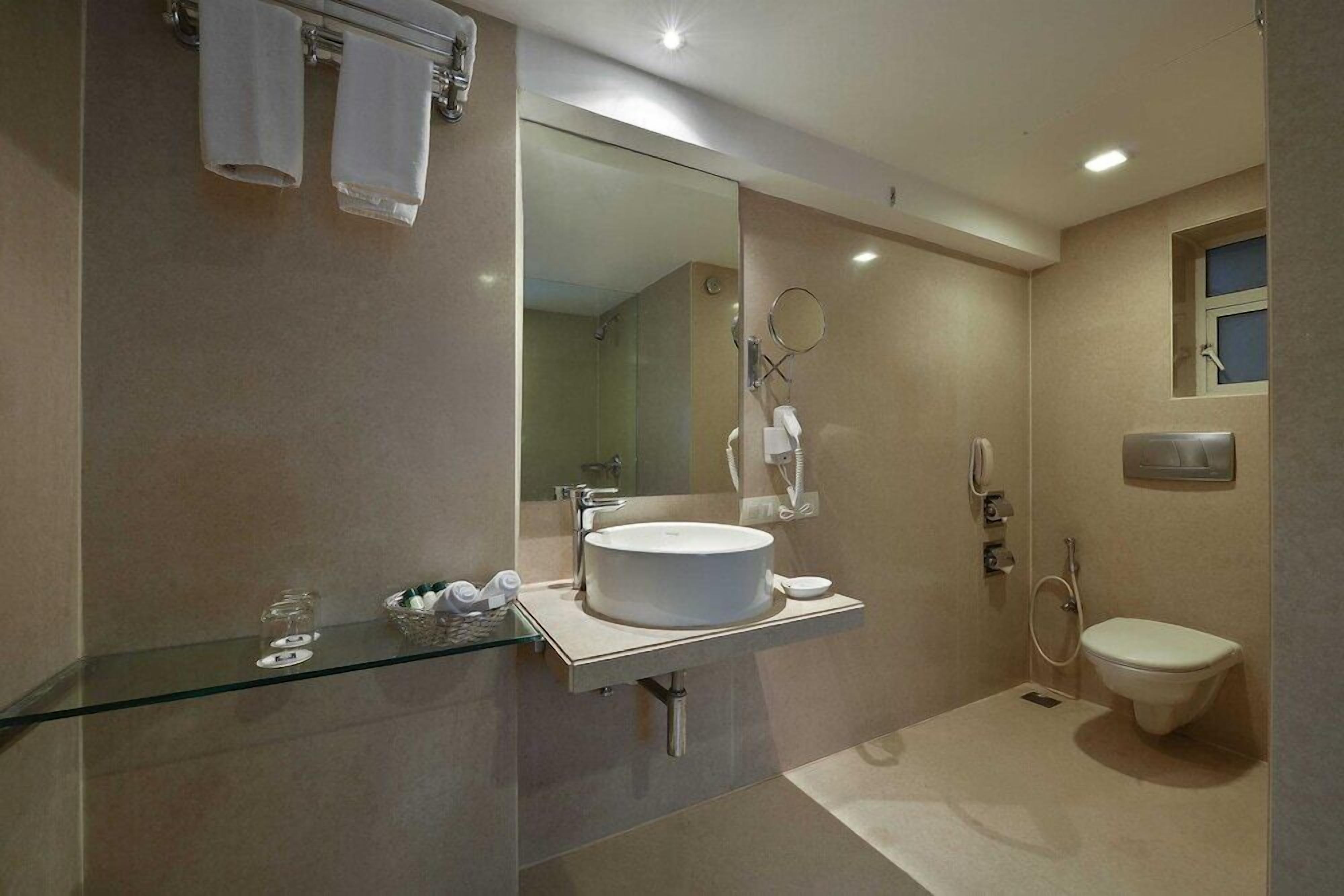 A modern bathroom with a glass shower enclosure, a white sink, and a toilet.
