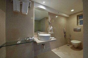 A modern bathroom with a glass shower enclosure, a white sink, and a toilet. - Hotel Heritage (Mumbai)