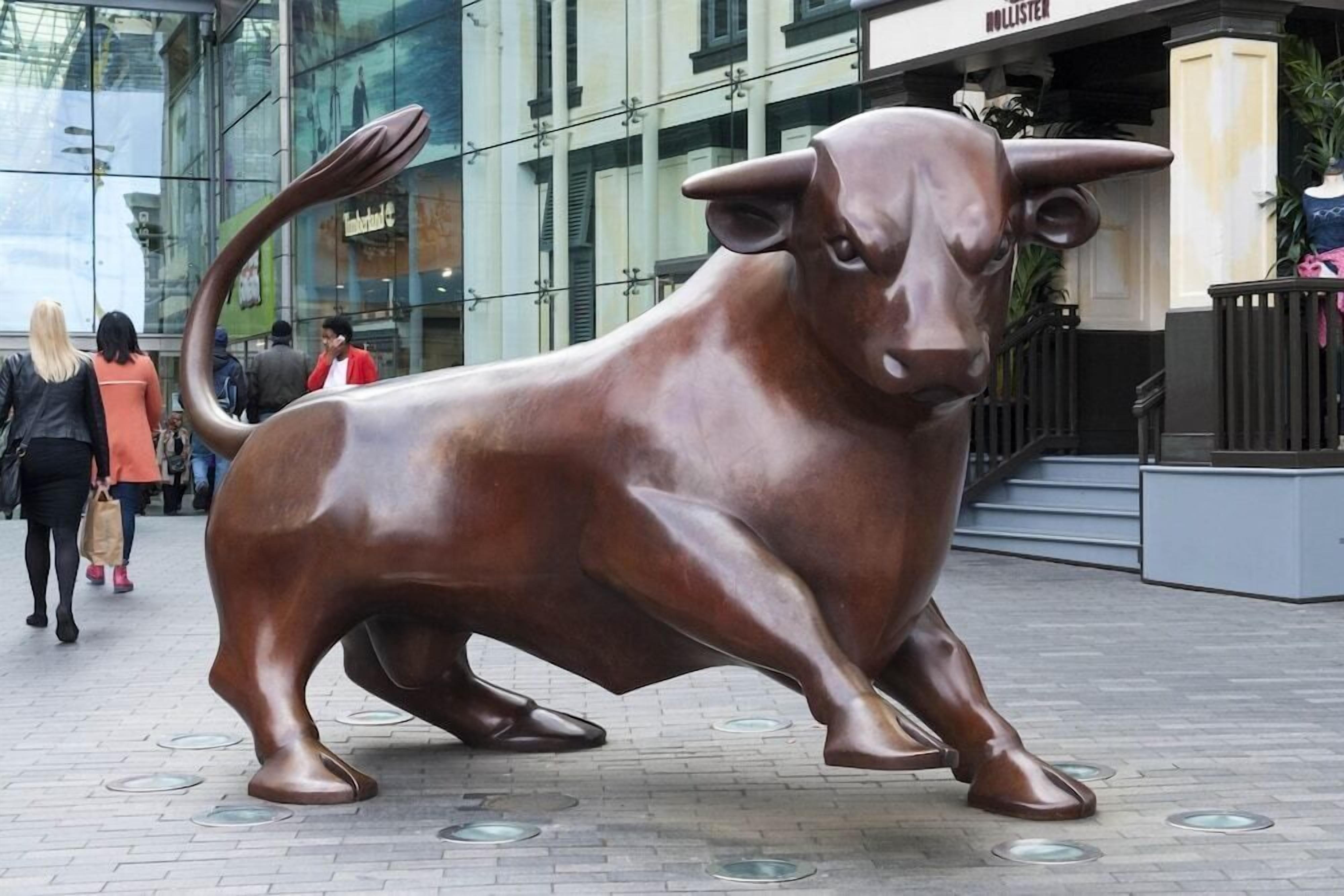 A bronze bull sculpture in an urban setting.